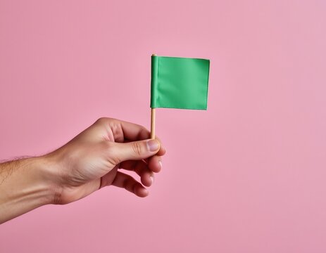 Person Holding Vibrant Green Flag Against Pastel