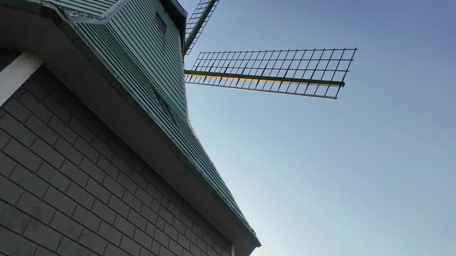 Low angle view looking up at rotating traditional Dutch windmill blades against a clear blue sky at Kasumigaura Sogo Park