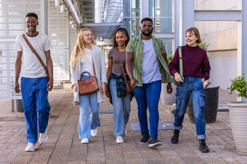Obraz premium Diverse students walking side-by-side on paved campus walkway carrying crossbody bags and flannel