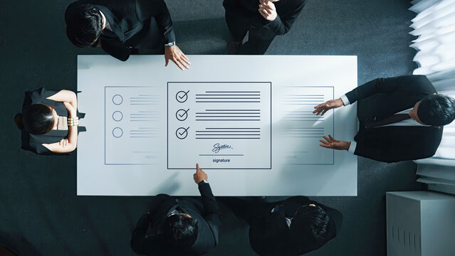 A group of professionals collaborates around a modern conference table, discussing important documents and signatures in a sleek office environment, emphasizing teamwork and strategy. Cyphers