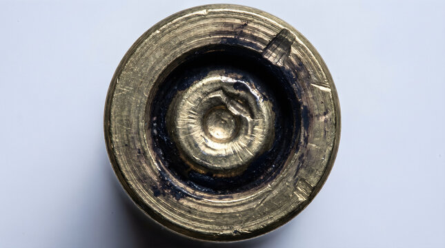 Macro of Spent Brass Cartridge Primer Pocket with Firing Pin Strike and Carbon Residue