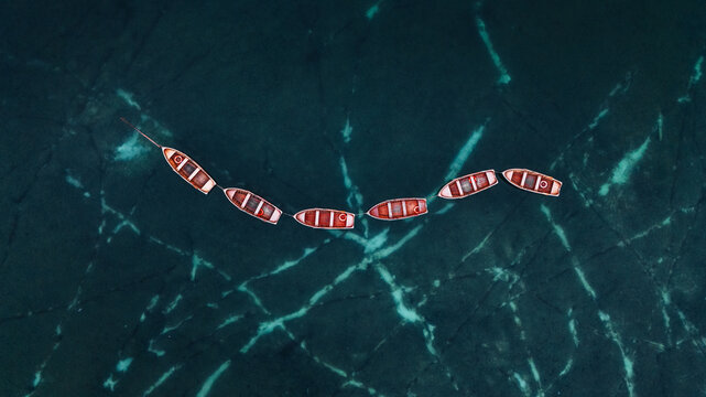 Aerial view of a line of wooden rowing boats floating on the turquoise water of Lake Braies in Braies, Trentino-Alto Adige, Italy.