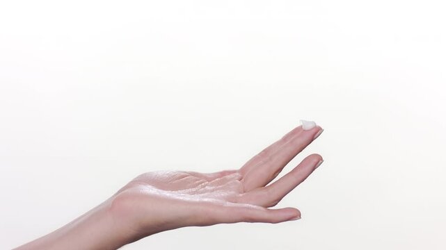 BCU shot of fair-skinned hand palm raising in frame with a drop of cream on it's finger on white background | skin care commercial concept