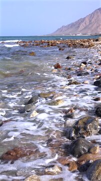 Seaside Cliffs And Mountain Views. Persian Gulf Picturesque Coast With Distant Mountain Scenery. Beautiful Rocky Coast Featuring Mountain Ranges Far In Background And Gentle Waves