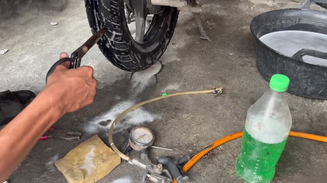 Close-up of Mechanic cutting rubber stopper to patch a punctured tubeless tire