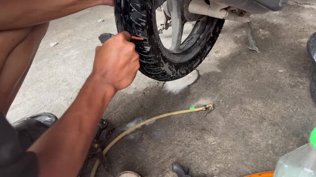 Close Up of Mechanic Inserting Plug into Punctured Tubeless Tire