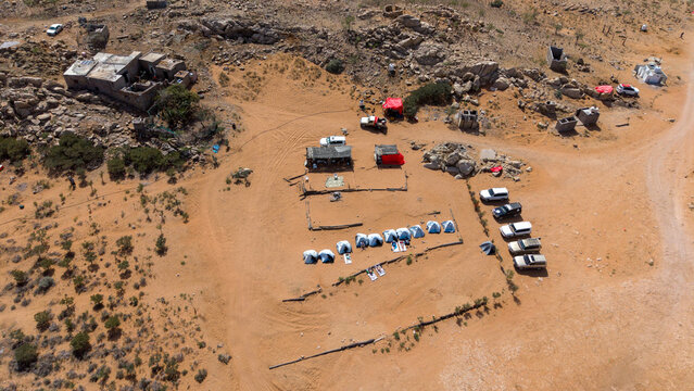 Aerial view of desert basecamp with tents and off-road vehicles. Sokotra, Yemen.