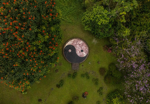 Aerial view of a Yin Yang symbol in a lush garden surrounded by flowering trees and vibrant greenery in Cinchona, Alajuela Province, Costa Rica.