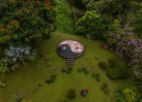 Aerial view of a circular Yin Yang symbol set in a lush garden surrounded by tropical trees and flowering plants in Cinchona, Alajuela Province, Costa Rica.
