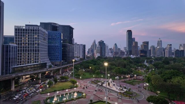 Bangkok, Thailand : Tilt down footage of sunset over Lumphini park in downtown Bangkok by Silom with BTS track above the busy street in the heart of Thailand capital city