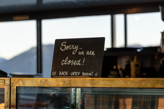 Handwritten chalkboard sign announcing temporary closure on a cafe counter