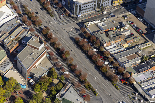 Aerial view of Lonsdale Street featuring commercial buildings, rows of trees with autumn foliage, and parked vehicles in Dandenong, Victoria, Australia.