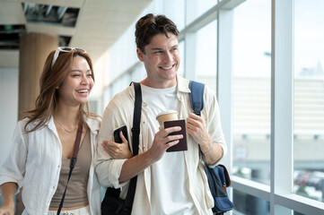 Obraz premium Happy asian woman girlfriend linking arms with white man boyfriend while walking in the airport.