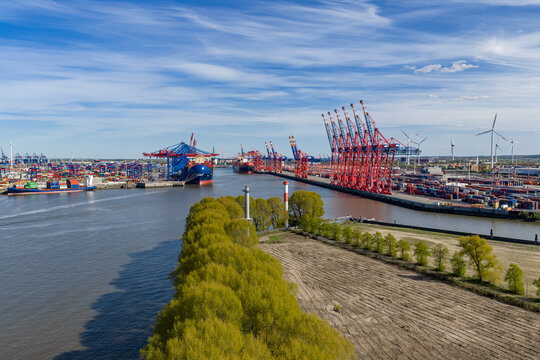 Aerial view of Waltershofer Hafen featuring red container cranes, cargo ships, and stacked containers along the Elbe river in Hamburg, Hamburg, Germany.