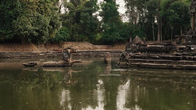 Ancient Khmer stone ruins reflected in calm temple pool in Cambodia