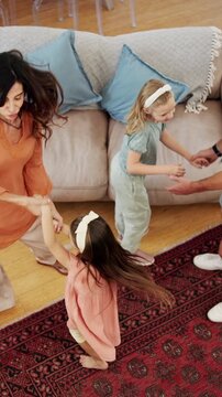 Parents, children and dancing in living room with family connection, bonding together and support. Above, happy people and music in home with mother, father and girl kids holding hands for rhythm.