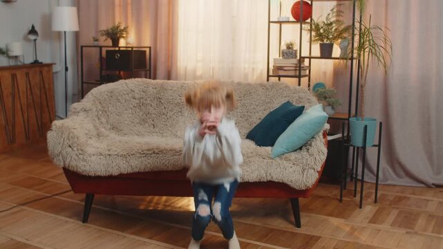 Young teenager girl stands at home performing simple squats and counting one, two, three with growing effort. Child kid sits on sofa finally collapses in laughter, feeling happy after a brief workout