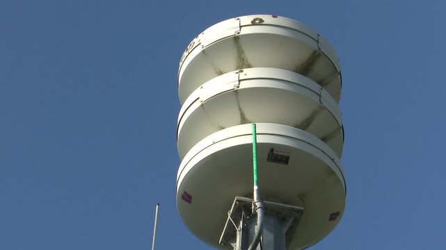 Close up of outdoor emergency siren with multiple speakers against blue sky
