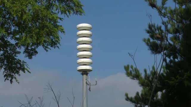 Outdoor emergency siren alert system mounted on a pole against a blue sky