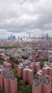 High angle drone view over New York City, New York showing red brick residential buildings, green courtyards and distant skyline, revealing density and structure of urban life.