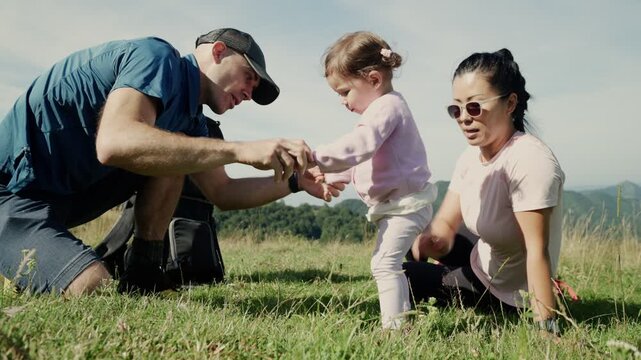 Multiethnic family helping toddler take her first steps in nature