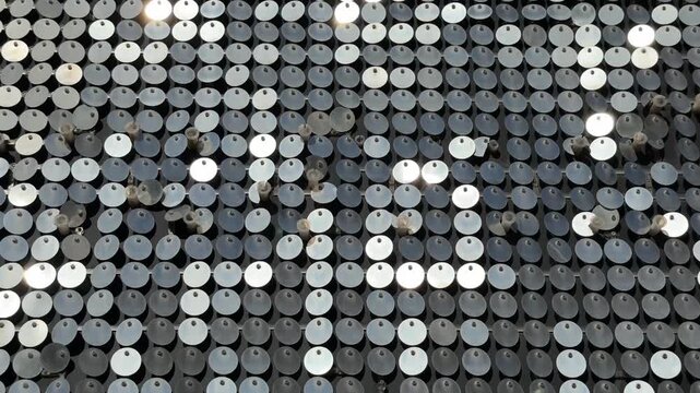 An abstract background of mirrored circular elements swaying in the wind and reflecting sunlight. 4K footage