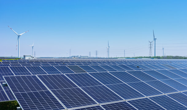 Vast Solar Farm with Wind Turbines at Coastal Renewable Energy Base Under Clear Blue Sky