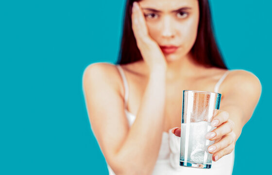 Woman taking a pill with a glass of water. Woman taking drugs to releave headache. Girl take some pills, holds glass of water