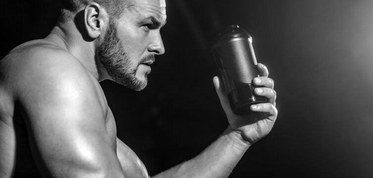 Drinks water in the gym. Man at gym and holding bottle of water. Muscular man drinking water. Black and white