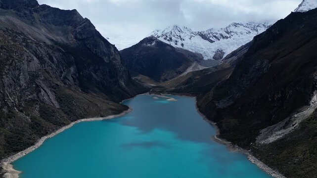 Huaraz, Peru: Forward footage of famous laguna paron in Caraz, Huaraz region, Peru. Surrounded by mountain range and with cloudy dramatic sky, showing cordillera blanca in the background