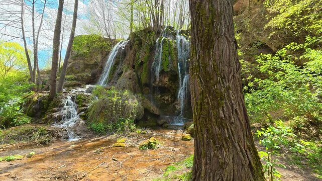 Lush green forest surrounds a flowing waterfall. Bigar Waterfall, Stara Planina. (Balkan Mountains), Serbia.