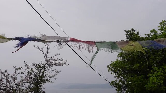 Colorful prayer flags fluttering in the wind over the sea with cherry blossoms