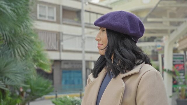 Woman with purple beret and visible face looking up on street in front of buildings; serenity hope curiosity.