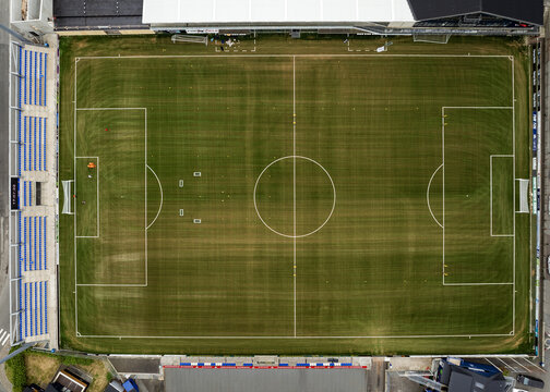 Aerial view of the green football pitch at Djupumyra Stadium with white markings and blue spectator stands in Klaksvik, Northern Isles, Faroe Islands.