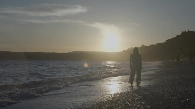 woman walking on the beach at susnet
