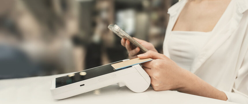 A woman pays at a cafe with a plastic card using a payment terminal. Small business settlements, accounting, and taxes for cash register and electronic payments. banner copy space
