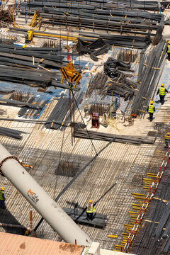 Aerial view of a busy construction site with workers installing steel rebar reinforcement and heavy machinery in Dubai, Dubai, United Arab Emirates.