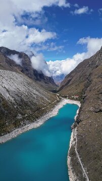 Huaraz, Peru: Forward footage of famous laguna paron in Caraz, Huaraz region, Peru. Surrounded by mountain range and with cloudy dramatic sky hiding cordillera blanca in the background
