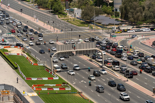 Aerial view of a busy multi-lane road intersection with heavy traffic, vehicles, and green landscaping under bright daylight Dubai, Dubai, United Arab Emirates.