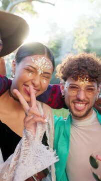 Face, smile and friends at music festival, outdoor and laughing at social gathering with peace sign. Portrait, excited and funny people at party with gems, hand gesture and tongue out for rave