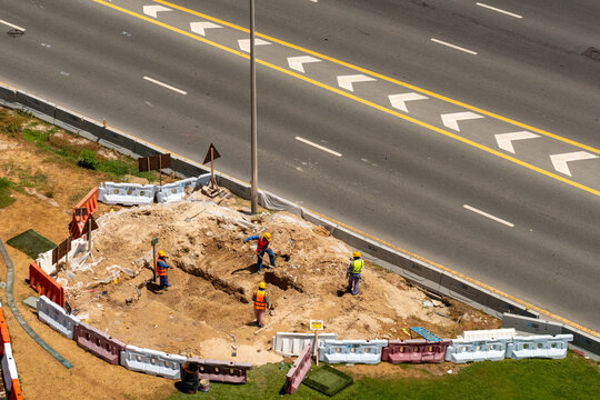 Aerial view of construction workers in safety vests digging a trench at a construction site in Dubai, Dubai, United Arab Emirates.