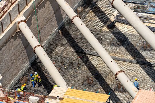 Aerial view of construction workers in safety gear working on a steel rebar foundation with large white support struts in Dubai, Dubai, United Arab Emirates.