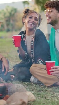 Drinks, friends and relax at festival by fire, social gathering and laughing together outdoor. Party, group and people with alcohol at event, happiness and hangout with funny joke for celebration