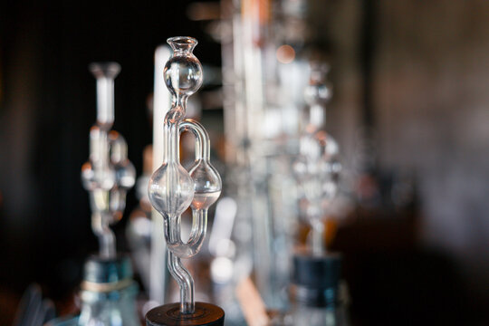 Glass fermentation airlock equipment on brewing bottle creates an intriguing atmosphere for winemaking process with clear bubbler device against dark background