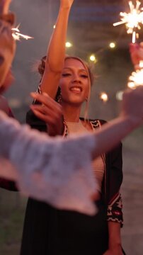 Outdoor, dance and friends with sparklers at festival, party and listening to music concert together. Night, event and people with fireworks for celebration, gathering and happy for festive season