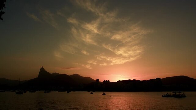 Sunset view from Mureta da Urca over Guanabara Bay in Rio de Janeiro, Brazil. Golden hour landscape with sailboats.