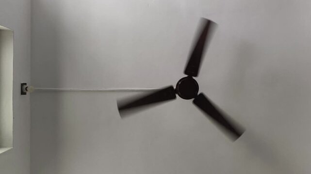 Wall mount noiseless bldc ceiling fan blades spinning or rotating for air cooling, flow and circulation inside room. Energy wastage, power consumption, electric current and using electricity concept.