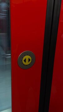 Operator interacts with station control button. Person presses yellow button on train panel amid station environment and station backdrop