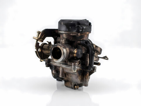 Fire-damaged and charred motorcycle carburetor on a white background