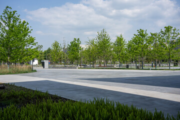 Fototapeta premium urban park square with green trees and lawn under blue sky